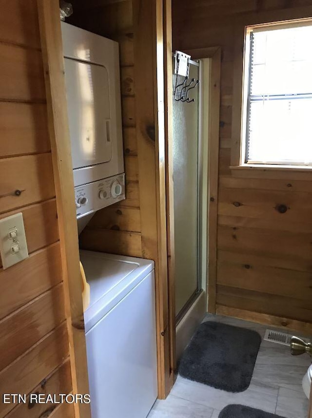 washroom with stacked washer and dryer and wood walls