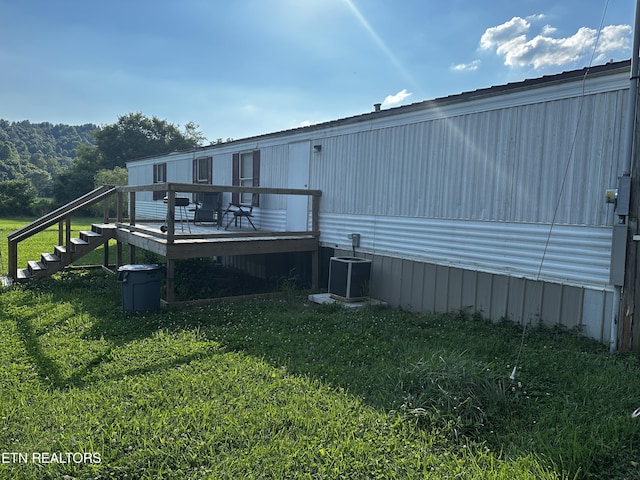 exterior space featuring central AC unit, a wooden deck, and a yard