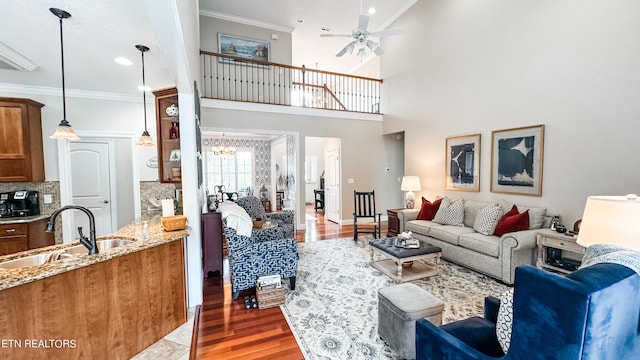 living room featuring ornamental molding, ceiling fan with notable chandelier, dark hardwood / wood-style floors, and sink