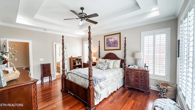 bedroom with ceiling fan, a raised ceiling, ensuite bath, ornamental molding, and dark hardwood / wood-style flooring