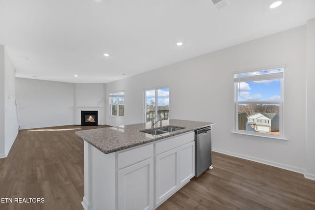 kitchen featuring dishwasher, sink, white cabinetry, a kitchen island with sink, and stone countertops