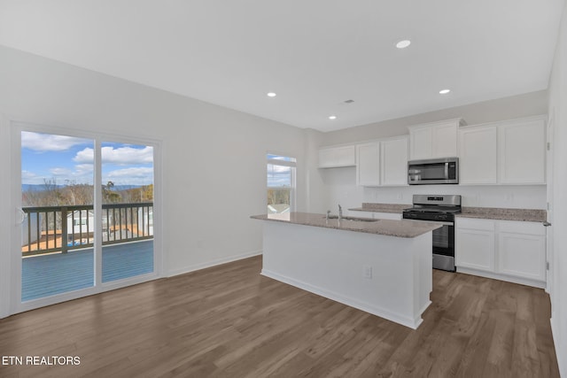 kitchen with appliances with stainless steel finishes, sink, white cabinets, and a kitchen island with sink