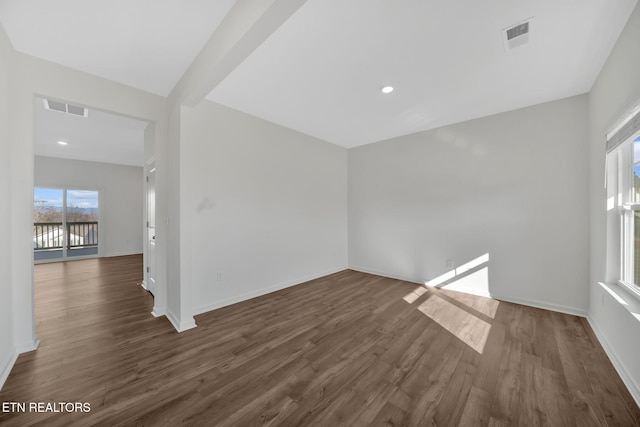 spare room with dark hardwood / wood-style flooring and beam ceiling