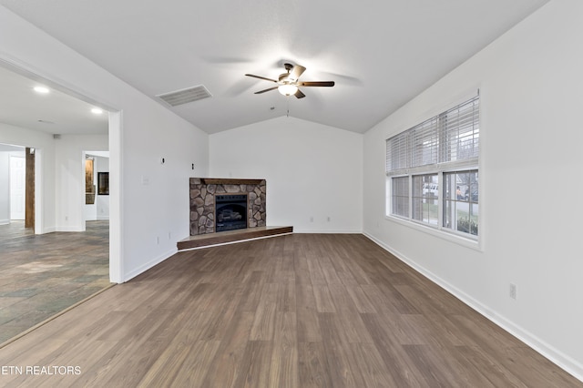 unfurnished living room with hardwood / wood-style flooring, a stone fireplace, ceiling fan, and lofted ceiling