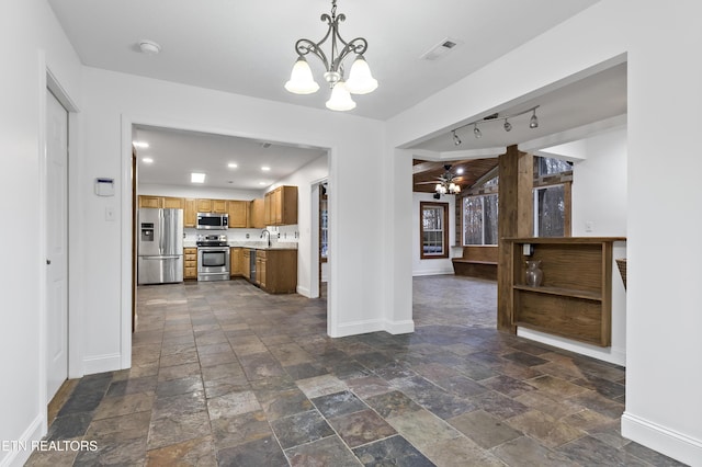 kitchen featuring sink, rail lighting, a chandelier, pendant lighting, and appliances with stainless steel finishes