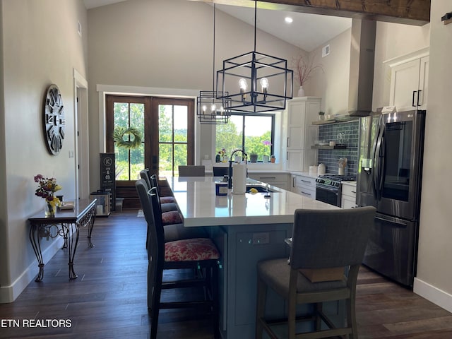 kitchen with tasteful backsplash, white cabinets, black fridge, range with gas cooktop, and dark wood-type flooring