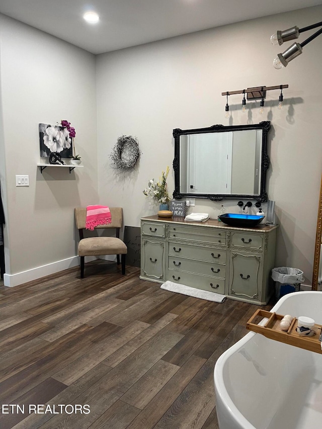 bathroom featuring wood-type flooring, a bath, and dual bowl vanity