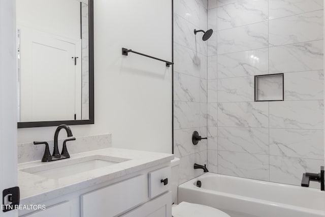 full bathroom featuring tiled shower / bath, vanity, and toilet