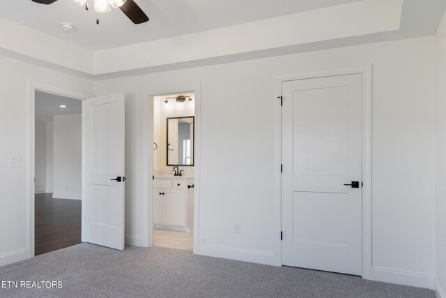 unfurnished bedroom featuring sink, light colored carpet, and ensuite bathroom