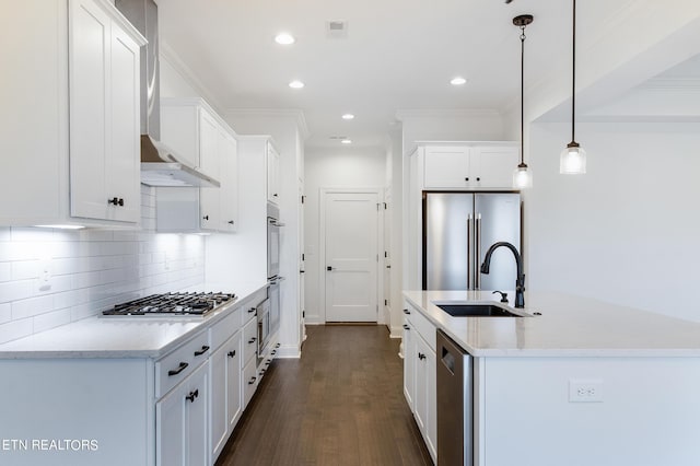 kitchen featuring sink, white cabinetry, appliances with stainless steel finishes, pendant lighting, and wall chimney range hood