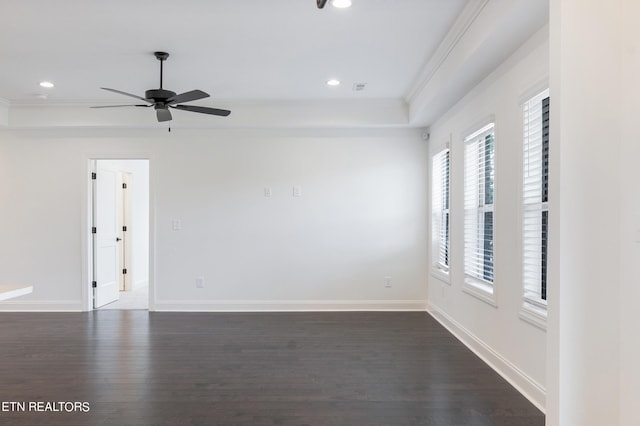 spare room with a raised ceiling, ornamental molding, dark wood-type flooring, and ceiling fan