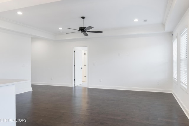 unfurnished room with a raised ceiling, crown molding, ceiling fan, and dark hardwood / wood-style flooring