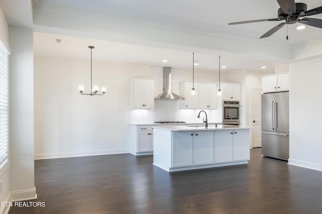 kitchen with white cabinetry, hanging light fixtures, high quality fridge, a center island with sink, and wall chimney exhaust hood