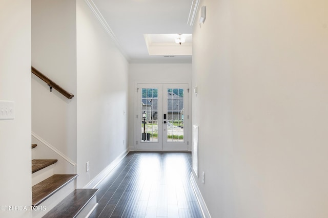 entryway with ornamental molding, a tray ceiling, dark hardwood / wood-style flooring, and french doors