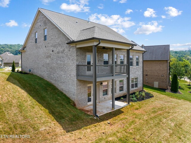 rear view of house featuring a balcony, a patio, and a yard