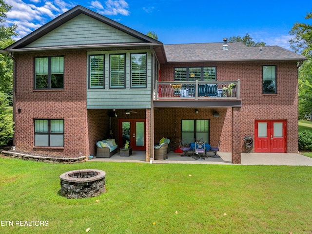 rear view of house with a patio, a balcony, a lawn, and a fire pit