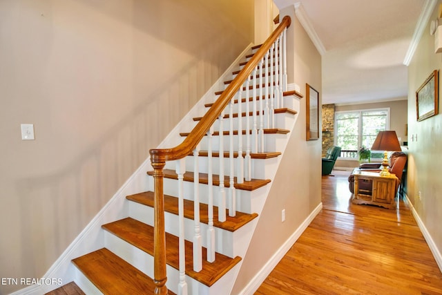 staircase with hardwood / wood-style flooring and ornamental molding