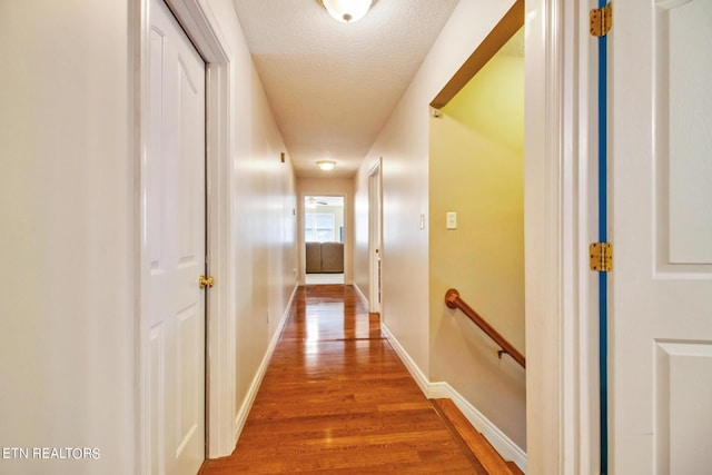 hall with a textured ceiling and hardwood / wood-style flooring