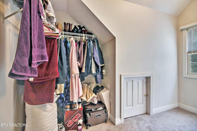 spacious closet with lofted ceiling and light carpet