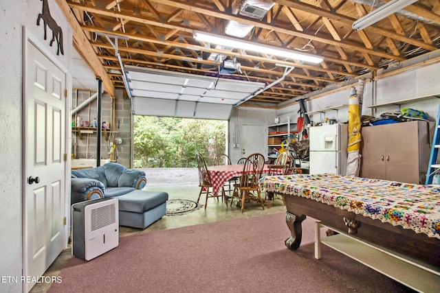 garage featuring a garage door opener and white refrigerator with ice dispenser