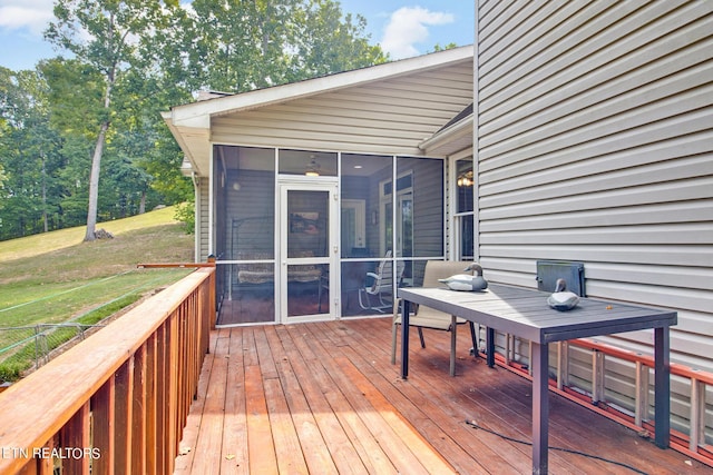 wooden terrace with a sunroom and a lawn