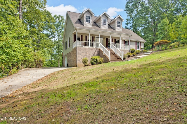 cape cod home featuring a front lawn, a garage, and a porch