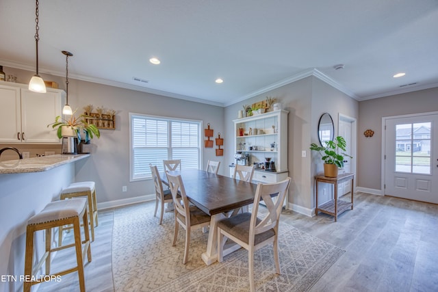 dining room with ornamental molding and light hardwood / wood-style floors