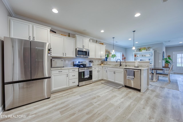 kitchen featuring stainless steel appliances, sink, hanging light fixtures, and white cabinets