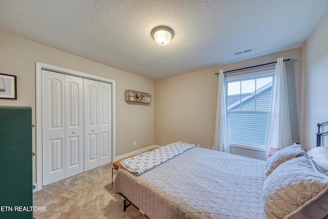 carpeted bedroom featuring a textured ceiling and a closet