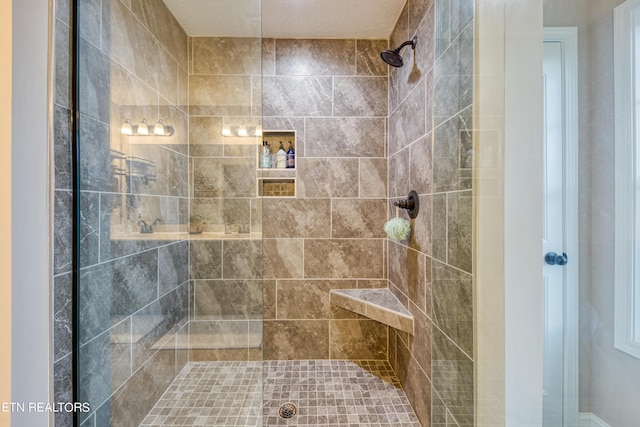 bathroom featuring a shower with shower door and a textured ceiling