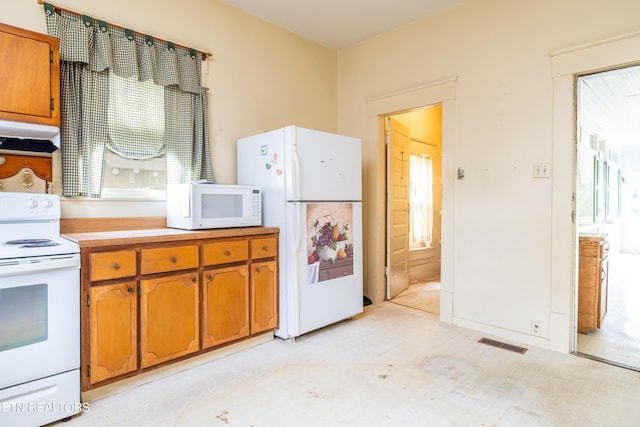 1227 N Main St, Sweetwater, TN 37874 - kitchen with under cabinet range hood, visible vents, brown cabinetry, and white appliances
