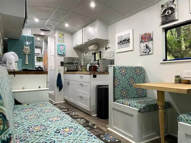 interior space with wood counters, sink, tasteful backsplash, and white cabinets