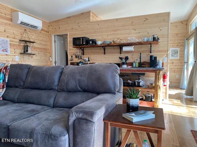 living room featuring hardwood / wood-style floors, vaulted ceiling, a wall mounted AC, and wood walls