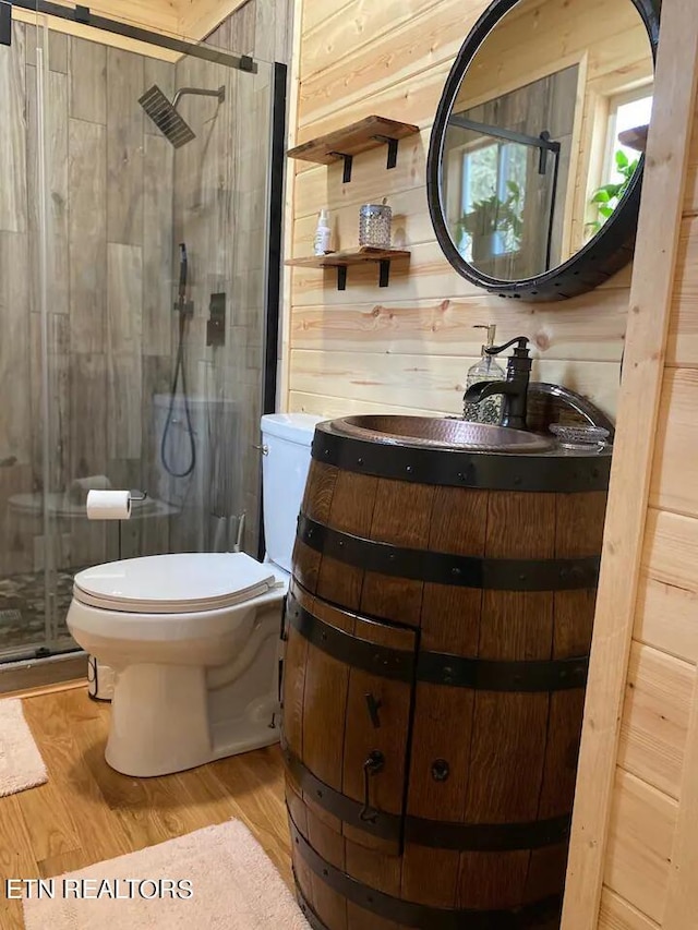 bathroom with toilet, wooden walls, a shower with door, and hardwood / wood-style floors