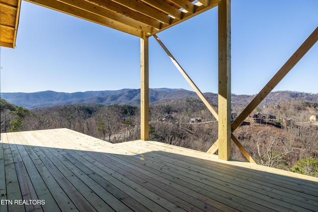 wooden terrace with a forest view and a mountain view