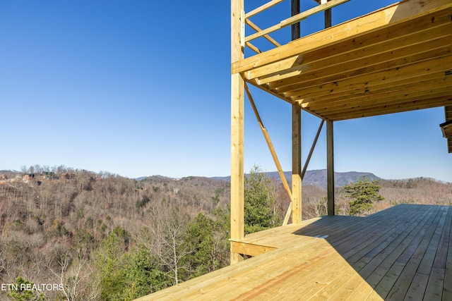 wooden terrace featuring a mountain view and a view of trees