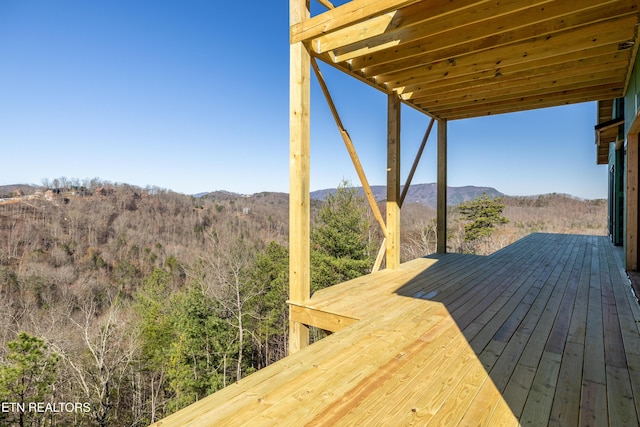 wooden deck with a wooded view and a mountain view