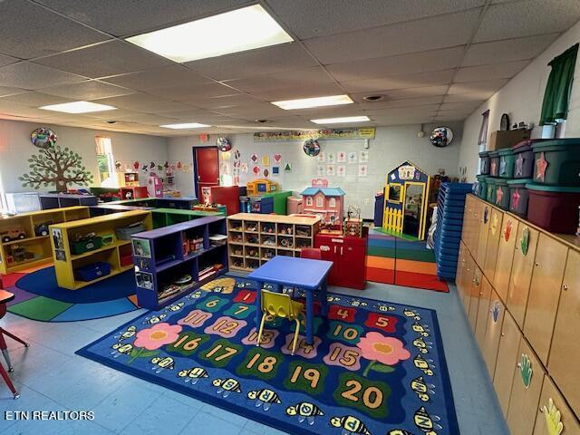 playroom with tile patterned floors and a drop ceiling
