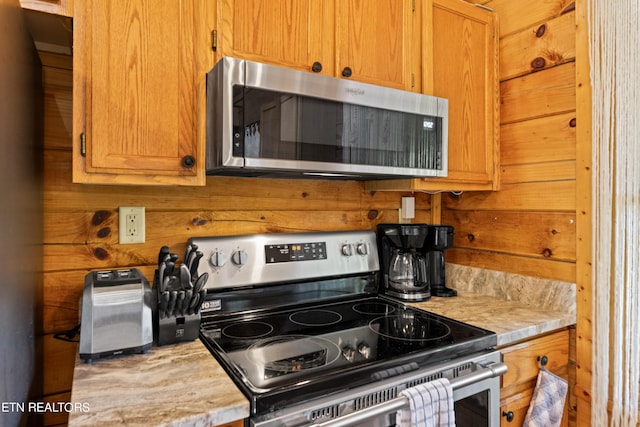 kitchen with appliances with stainless steel finishes and wood walls