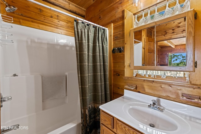 bathroom with vanity, wooden walls, and shower / bathtub combination with curtain