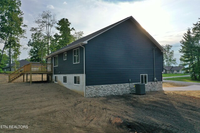 view of side of home featuring cooling unit and a wooden deck