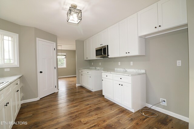 kitchen with dark hardwood / wood-style flooring, white cabinetry, and light stone countertops