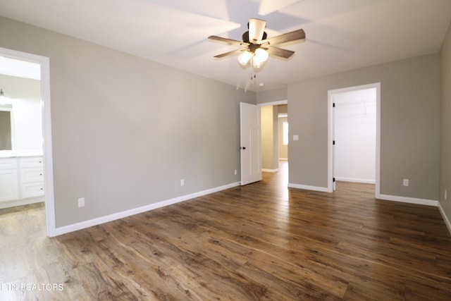 unfurnished bedroom with a spacious closet, wood-type flooring, ceiling fan, and connected bathroom