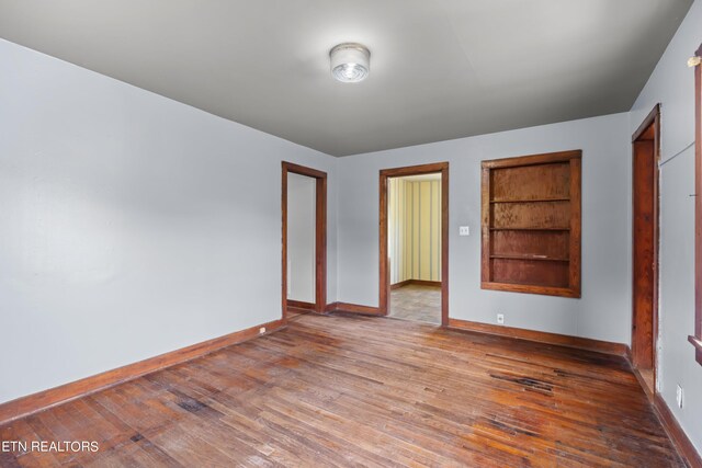 spare room with built in features and hardwood / wood-style floors