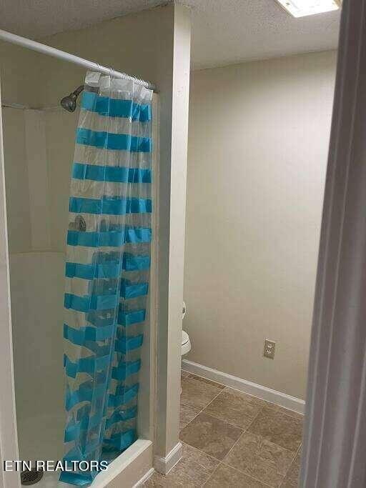 bathroom with toilet, tile patterned floors, and a textured ceiling