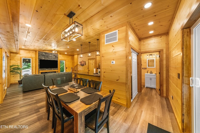 dining room featuring wood ceiling, sink, hardwood / wood-style floors, and wood walls