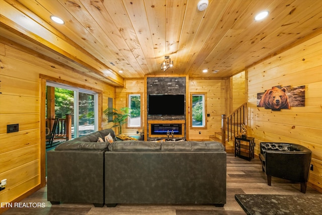 living room with a large fireplace, dark wood-type flooring, wooden ceiling, and wooden walls