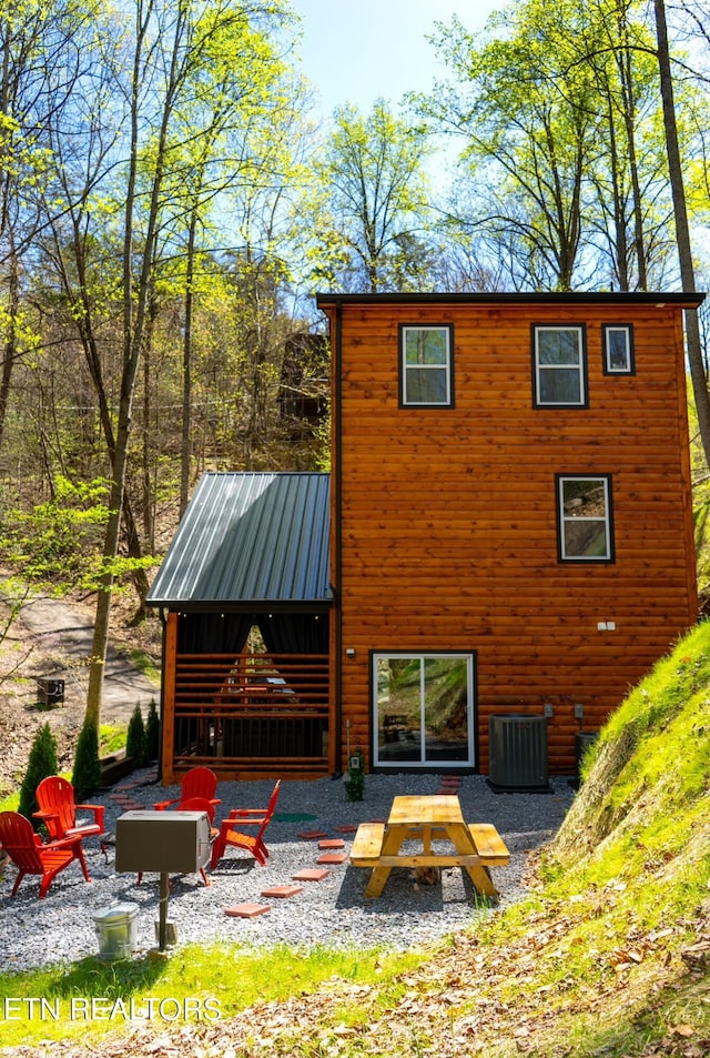 back of house featuring central air condition unit, a patio area, and a fire pit