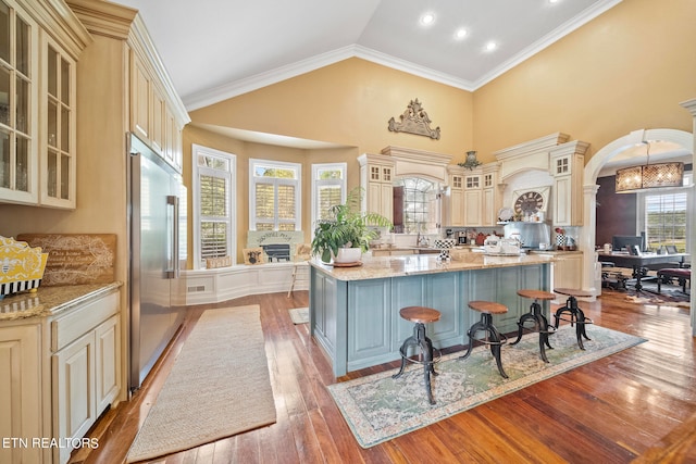 kitchen with cream cabinetry, crown molding, a center island, light hardwood / wood-style flooring, and high end refrigerator