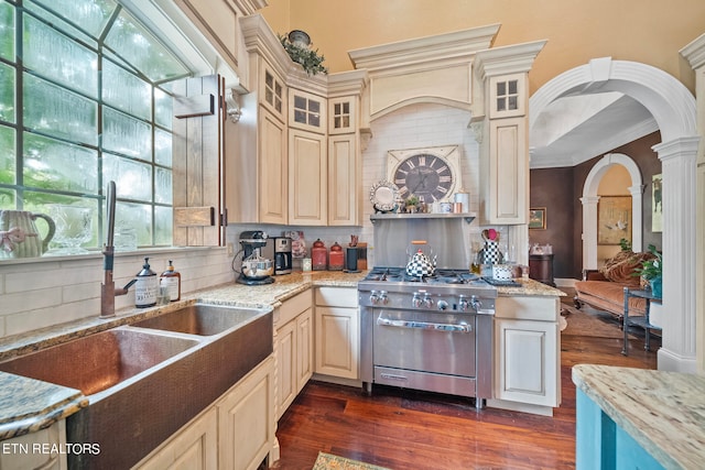 kitchen with high end stainless steel range, crown molding, backsplash, dark wood-type flooring, and ornate columns